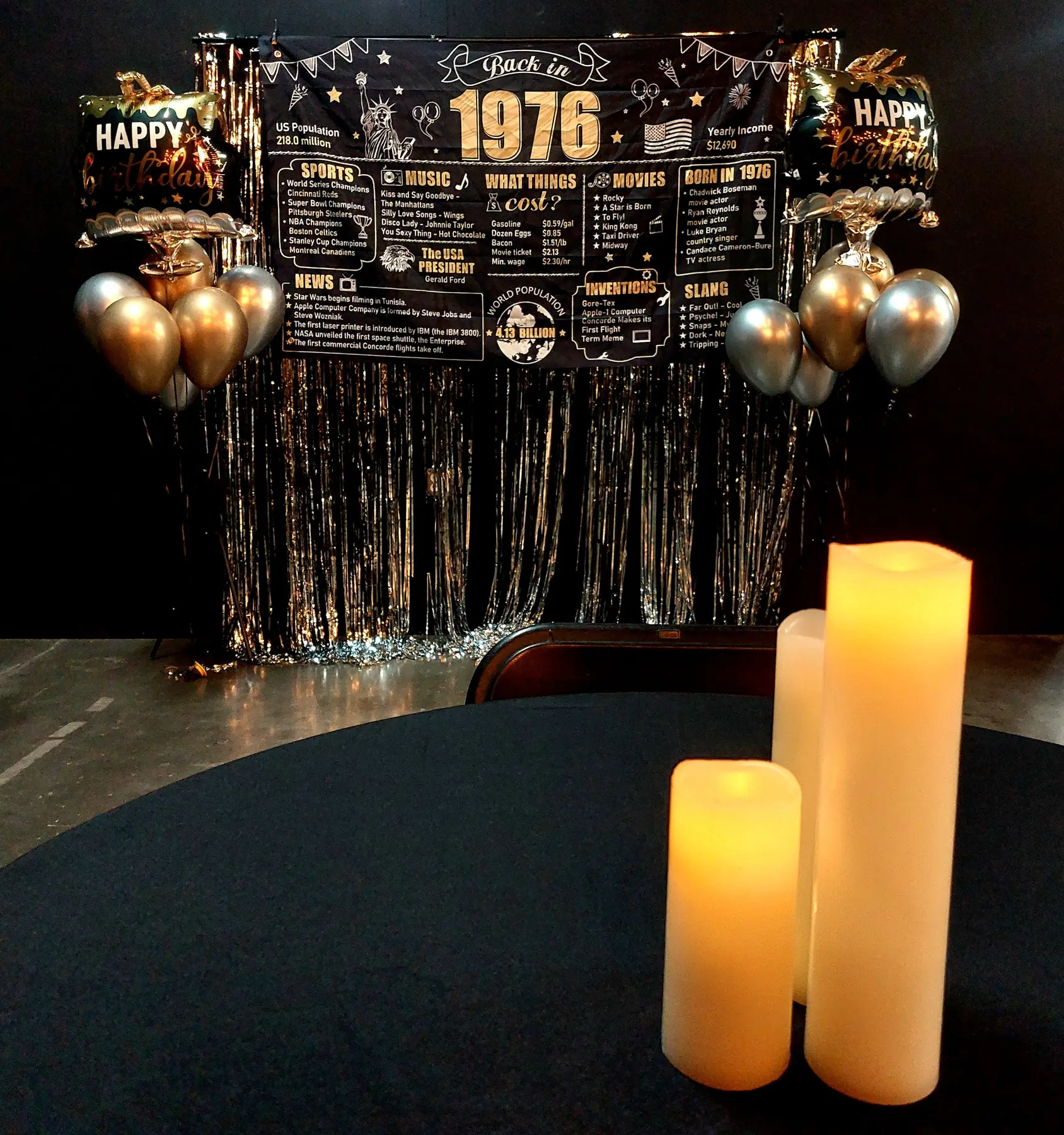 A festive birthday photo backdrop with balloons and glowing candles