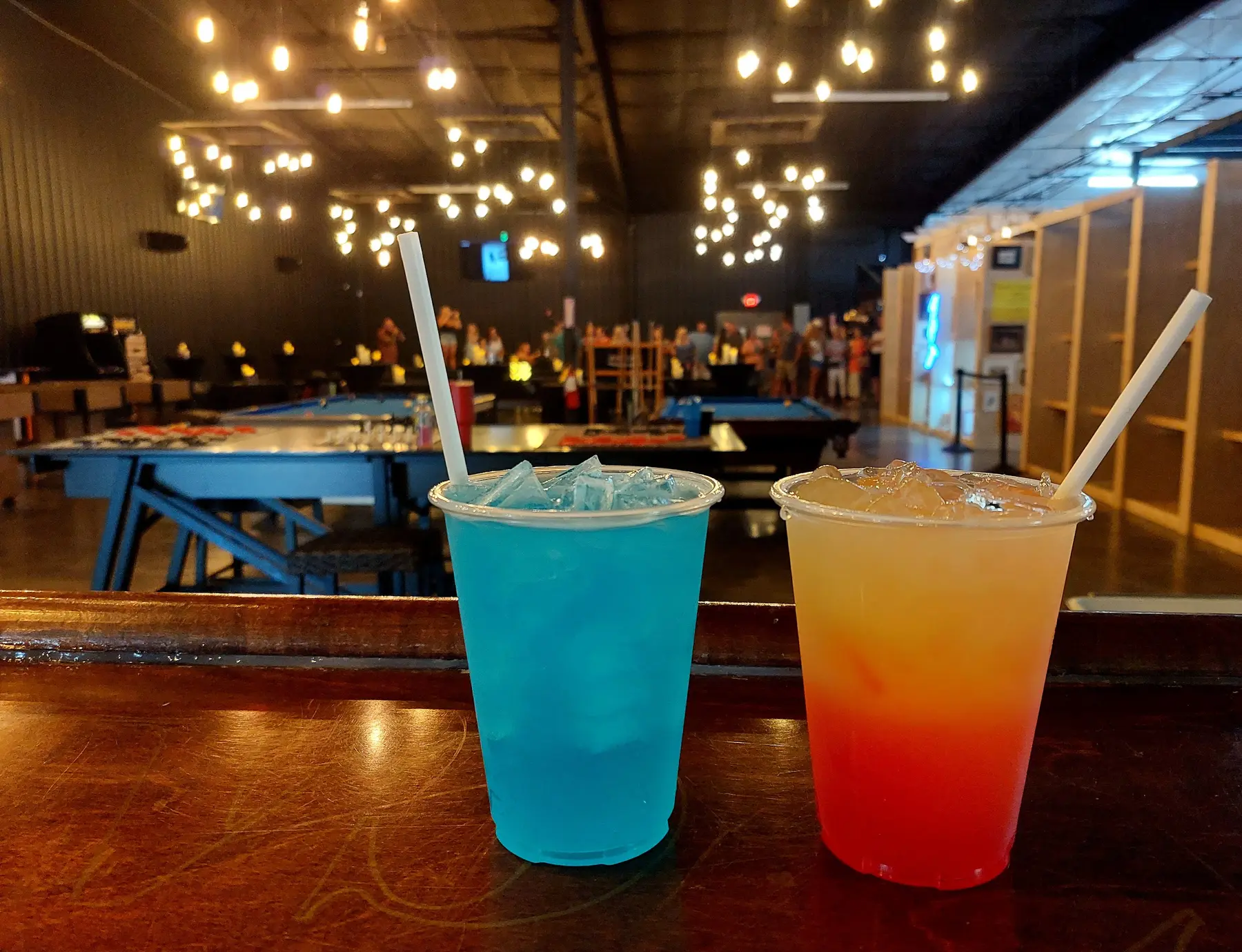 Colorful signature drinks with event guests gathered in the venue behind them